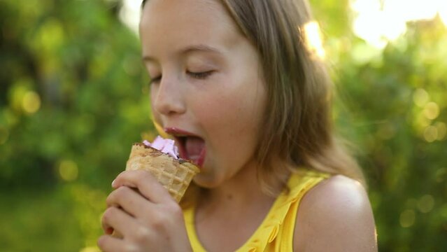 Cute girl with braces eating italian ice cream cone smiling while resting in park on summer day, child enjoying ice cream outdoor, happy holidays, summertime