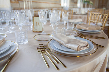 Hall of an ancient castle with catering for wedding events. The tables are set up with fine plates, glasses and cutlery