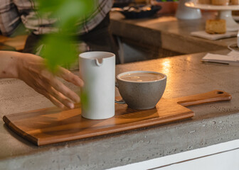 Person serving coffee on a wooden platter on the counter