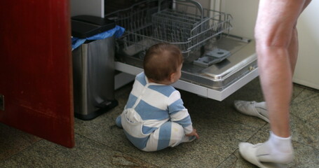 Cute baby on kitchen floor next to dishwasher appliance, infant toddler crawling at kitchen home