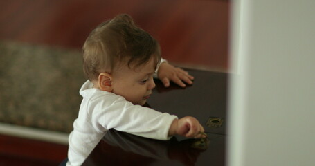 Fototapeta premium Cute baby leaning home furniture playing with table top