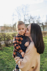 mom hugs and holds her son in her arms in a summer park. Happy childhood. Parental care
