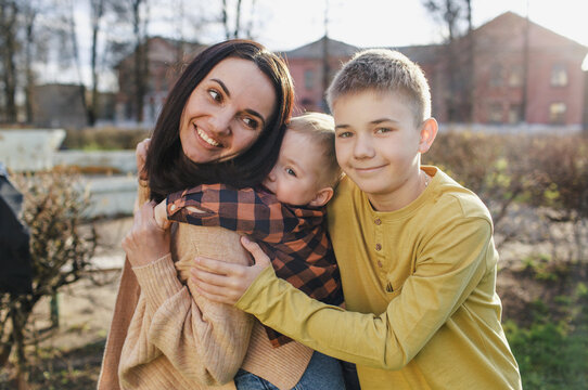 a happy mom plays with her two sons in a spring park