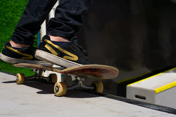 Close up of an unrecognizable skater doing a stunt on the ramp or quarter pipe. Youth, leisure activities and extreme sports concept.