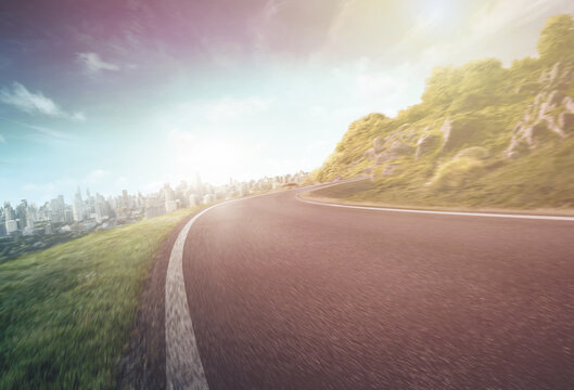 Empty long mountain road to the horizon on a sunny summer day at a bright sunset - speed motion blur effect.