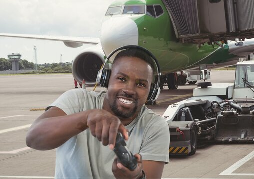 Composite image of african american man playing video games against airplane at the airport