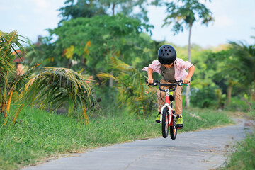 Country cycling walk. Young rider kid in helmet and sunglasses riding bicycle. Happy child have fun on empty trail. Active family lifestyle, sports, outdoor recreational activities on summer holidays. - Powered by Adobe