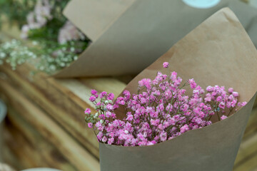 Bukiet suszonych różowych kwiatów w szarym papierze. - obrazy, fototapety, plakaty