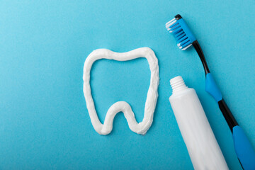 Tooth symbol made from toothpaste and a toothbrush on a blue background. Refreshing and whitening...