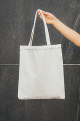 Female hand on the street holding white eco bag, mock up