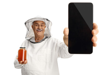 Bee keeper in a uniform holding a jar of honey and showing a smartphone