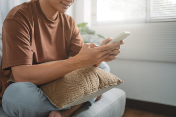 Young attractive man sitting on  sofa using smart phone at home.