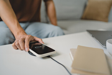 Man hands plugging a charger in a smart phone. Charging Smartphone with Wireless Charging Pad at Home