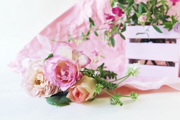 Fresh pink roses in a basket, flowers on a light background, the concept of a romantic greeting, a bridal bouquet, invitations, weddings, a card, packaging or sale in a flower shop