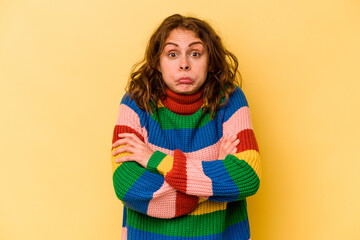 Young caucasian woman isolated on yellow background shrugs shoulders and open eyes confused.