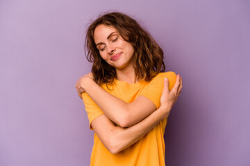 Young caucasian woman isolated on purple background hugs, smiling carefree and happy.