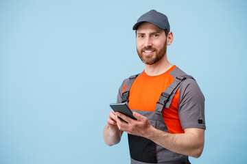 Smiling male worker in uniform holding mobile phone and looking at camera 