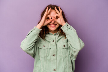Young caucasian woman isolated on purple background excited keeping ok gesture on eye.