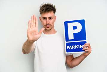 Young caucasian man holding parking placard isolated on white background standing with outstretched hand showing stop sign, preventing you.