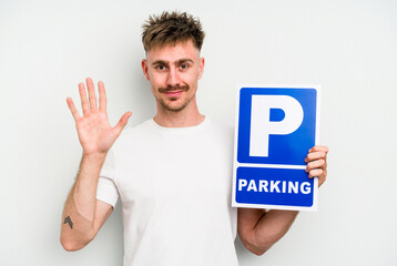 Young caucasian man holding parking placard isolated on white background smiling cheerful showing number five with fingers.