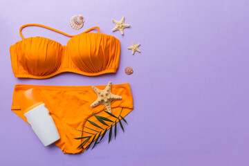 Woman swimwear and beach accessories flat lay top view on colored background Summer travel concept. bikini swimsuit, straw hat and seasheels. Copy space Top view