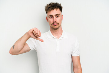 Young caucasian man isolated on white background showing a dislike gesture, thumbs down....