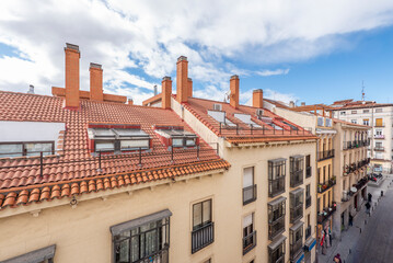 Facades of urban residential buildings with clay roofs, skylights and terraces