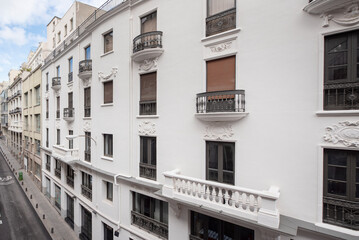 Naklejka premium White painted vintage building facade in a narrow street in the center of Madrid