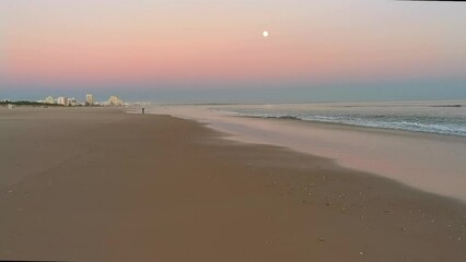 Beach at sunset almost empty with the full moon in the sky. Near La Raya with Spain, The Algarve, Portugal
