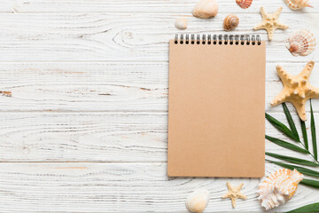 Blank writing book with summer beach accessories on background, copy space. Flat lay with copy space