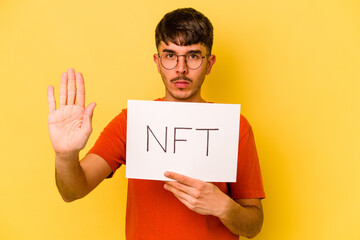 Young hispanic man holding nft placard isolated on yellow background standing with outstretched...