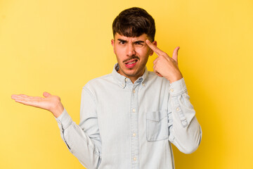 Young caucasian man isolated on yellow background showing a disappointment gesture with forefinger.