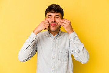 Young caucasian man isolated on yellow background doubting between two options.