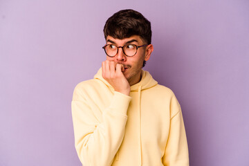 Fototapeta premium Young caucasian man isolated on purple background biting fingernails, nervous and very anxious.