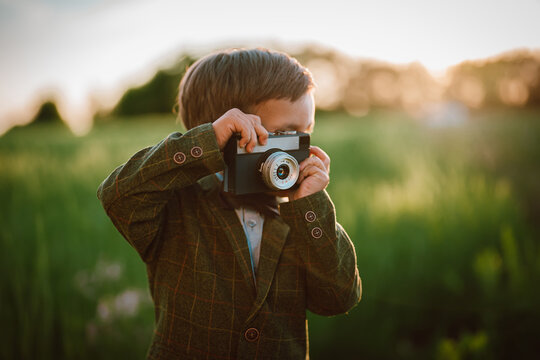 Hipster little boy with vintage camera outdoors. Child in costume