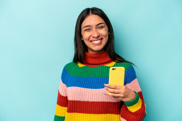 Young caucasian woman holding mobile phone isolated on blue background happy, smiling and cheerful.