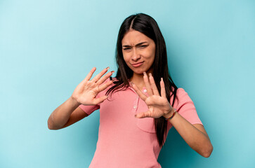 Young hispanic woman isolated on blue background rejecting someone showing a gesture of disgust.