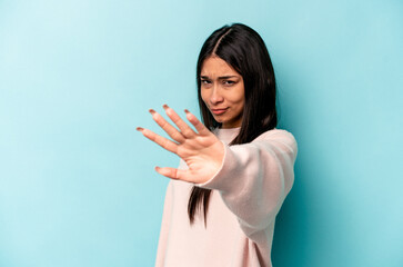 Young hispanic woman isolated on blue background rejecting someone showing a gesture of disgust.