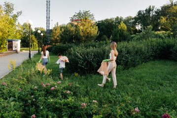 A group of adults and children together at sunset is engaged in garbage collection in the park....