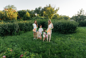 A group of adults and children together at sunset is engaged in garbage collection in the park....