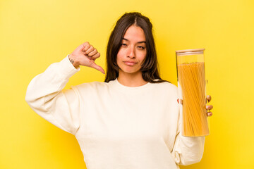 Young hispanic woman holding a spaghetti jar isolated on yellow background feels proud and self confident, example to follow.