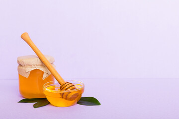 Honey in jar with leaves and honey dipper on colored background top view with copy text