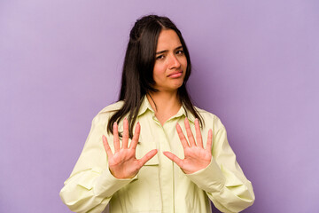 Young hispanic woman isolated on purple background rejecting someone showing a gesture of disgust.