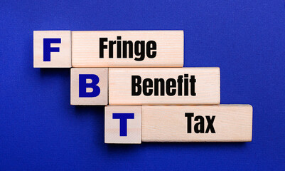 On a bright blue background, light wooden blocks and cubes with the text FBT Fringe Benefit Tax