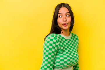 Young hispanic woman isolated on yellow background looks aside smiling, cheerful and pleasant.