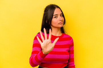 Young hispanic woman isolated on yellow background rejecting someone showing a gesture of disgust.