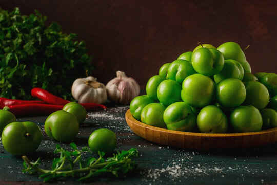 Tkemali, green cherry plum, with ingredients for sauce, on a wooden table, close-up, rustic, food background, no people, selective focus,