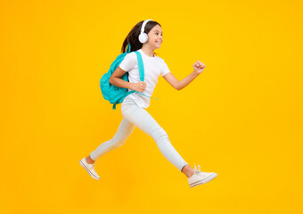 Fototapeta na wymiar School leisure. Happy teenager portrait. School girl in headphones on isolated studio background. School and music concept. Jump and run, jumping child.