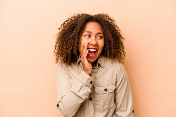 Young African American woman isolated on beige background shouting excited to front.