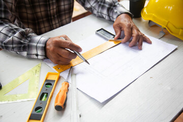 Architect asian old man drawings with blueprint  at Construction Site .concept